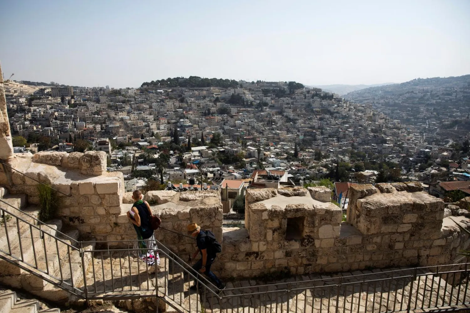 The Palestinian neighborhood of Silwan is seen in the background as people walk on a promenade on the surrounding walls of Jerusalem's Old City November 7, 2019. (Reuters)