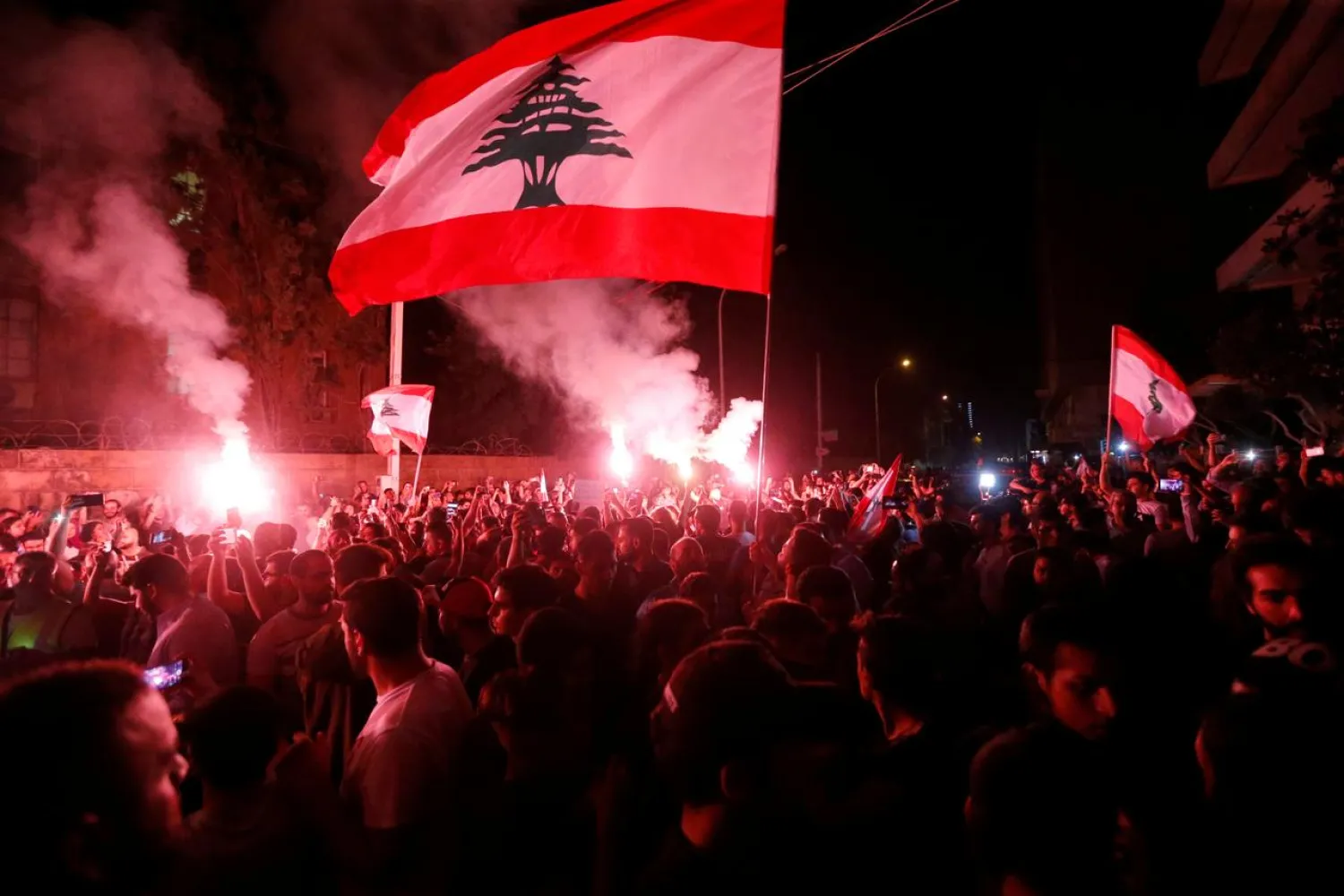 FILE PHOTO: Demonstrators hold flares and Lebanese flags as they protest outside the house of former Lebanese prime minister Fouad Siniora in Beirut, Lebanon November 7, 2019. REUTERS/Mohamed Azakir
