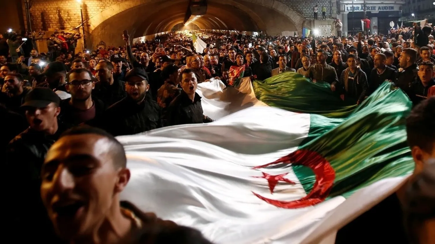 People carry a national flag as they celebrate on the streets of Algiers after President Abdelaziz Bouteflika submitted his resignation on April 2, 2019. (Reuters)