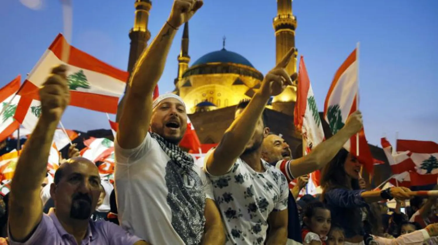 Anti-government protesters wave Lebanese flags and chant slogans, during ongoing demonstrations, in Beirut, Lebanon, Sunday, Nov. 10, 2019. (AP Photo/Bilal Hussein)