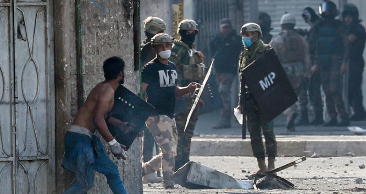 محتج يهم برمي حجر على عناصر أمن خلال مواجهات وسط بغداد أمس (أ.ب)