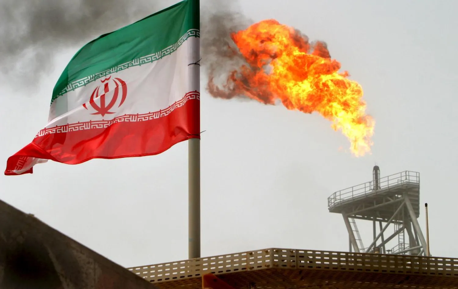 FILE PHOTO: A gas flare on an oil production platform in the Soroush oil fields is seen alongside an Iranian flag July 25, 2005. REUTERS/Raheb Homavandi/File Photo