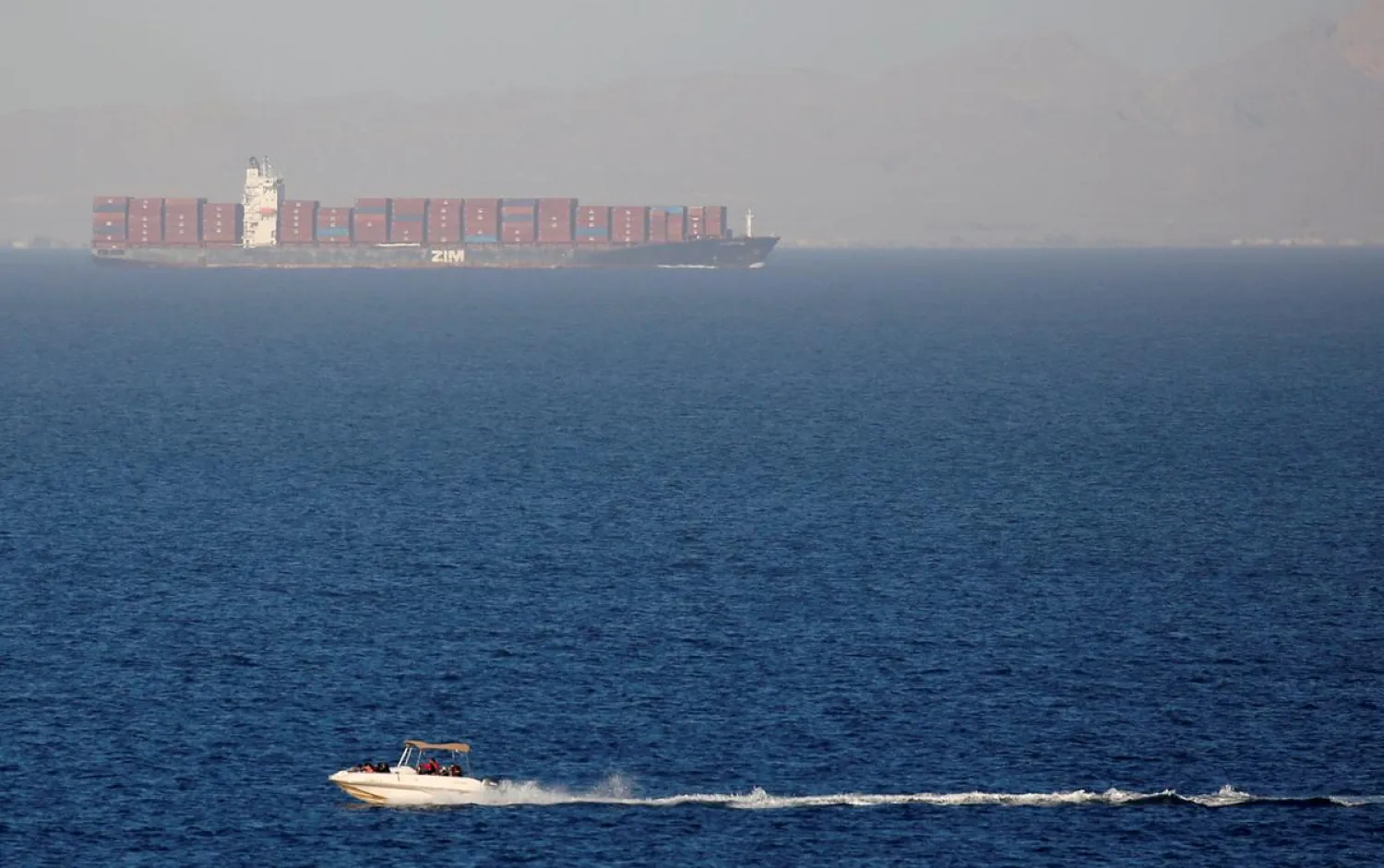 FILE PHOTO - People sail on a boat near a container ship crossing the Gulf of Suez towards the Red Sea before entering the Suez Canal, near El Ain El Sokhna in Suez, east of Cairo, Egypt, March 17, 2018. REUTERS/Amr Abdallah Dalsh