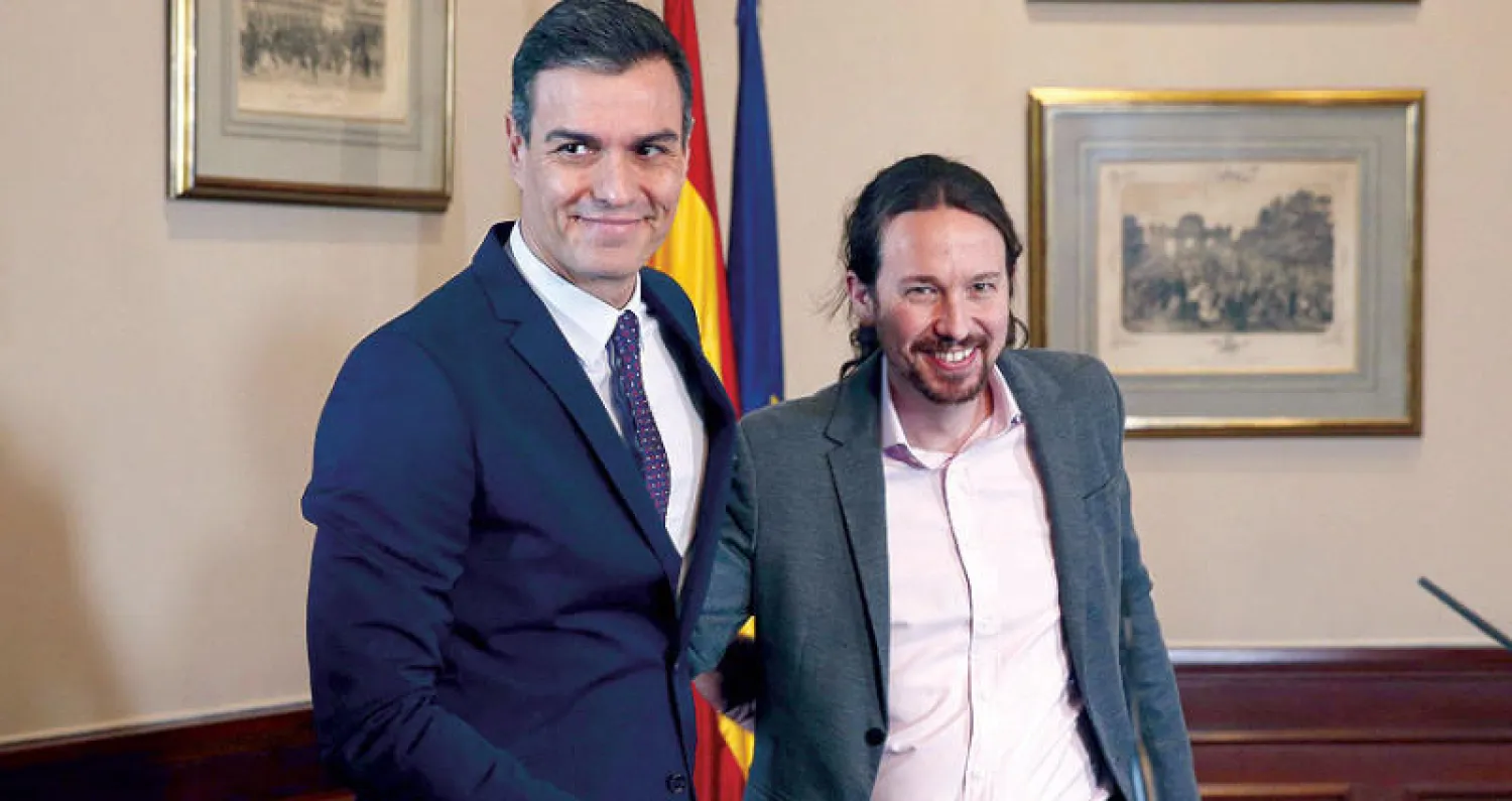 سانشيز وإغليسياس قبل توقيع اتفاق ائتلاف في مدريد أمس (إ.ب.أ)