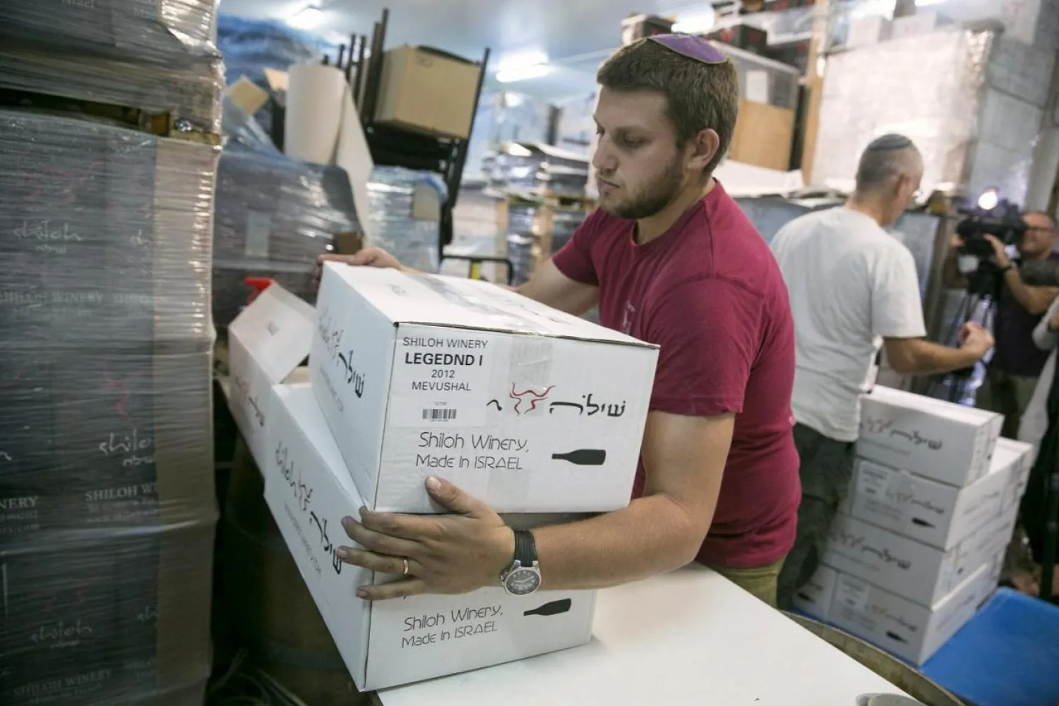 A worker carries boxes containing wine bottles for export at Shiloh Wineries, north of the West Bank city of Ramallah (File Photo: Reuters)

