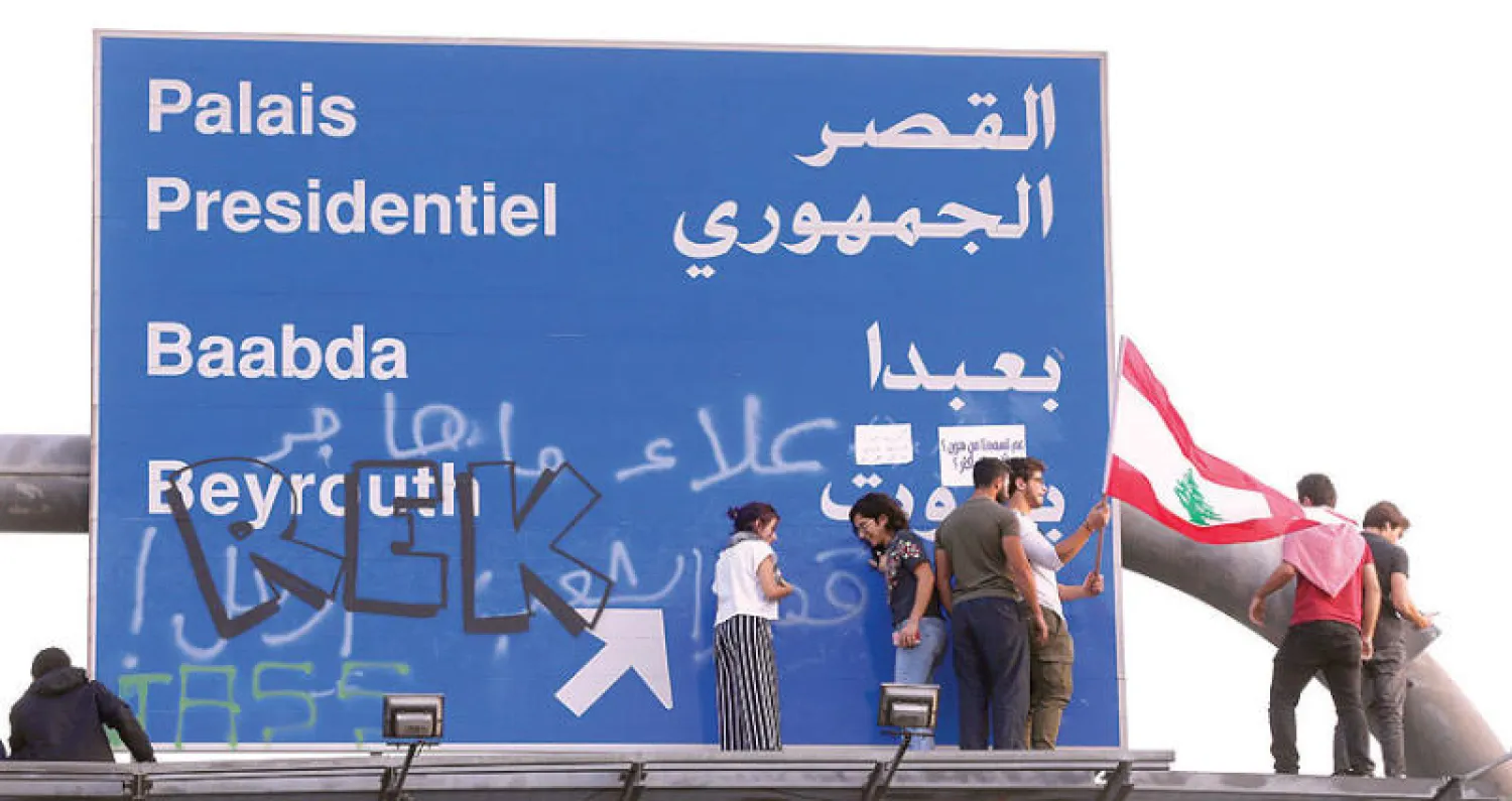 محتجون تسلقوا إلى علامة مرور ضخمة في منطقة الحازمية المؤدية إلى القصر الجمهوري في بيروت أمس (رويترز)