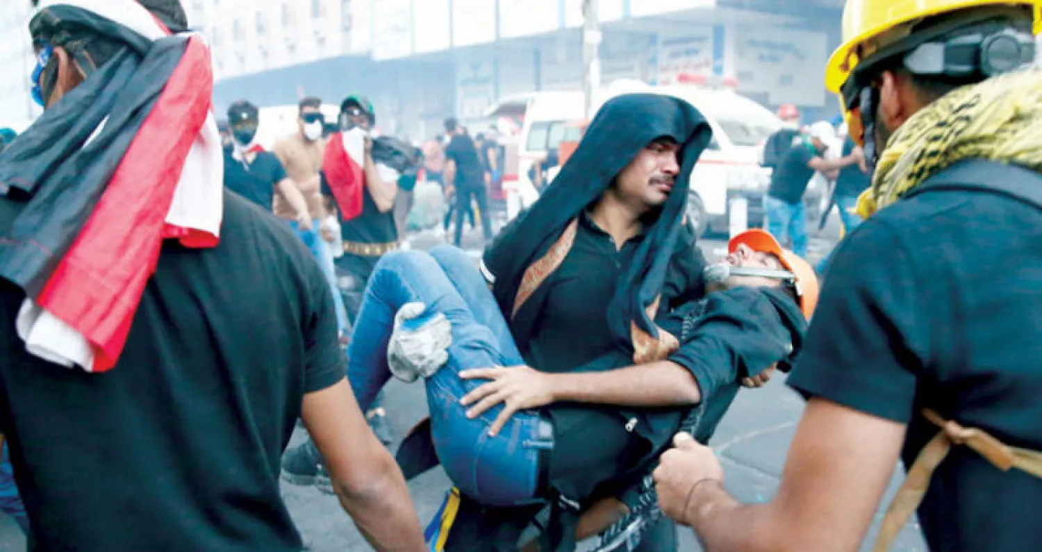 متظاهر يحمل رفيقا له أصيب في مواجهات مع قوات الأمن وسط بغداد أمس (رويترز)