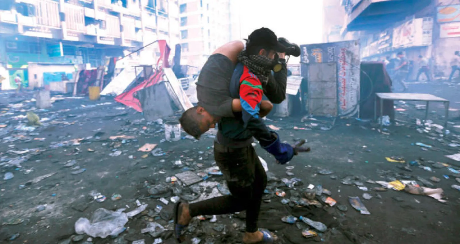 إجلاء أحد جرحى المواجهات بين المحتجين وقوات الأمن وسط بغداد أمس (أ.ب)