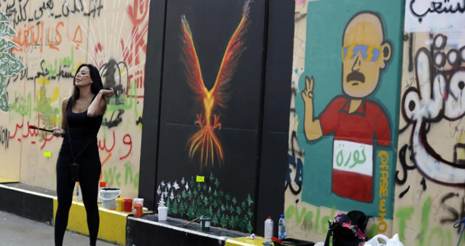الرسامة اللبنانية حياة نذير إلى جوار جدارية طائر الرخ (الفينيق) وسط العاصمة بيروت (أ.ف.ب)