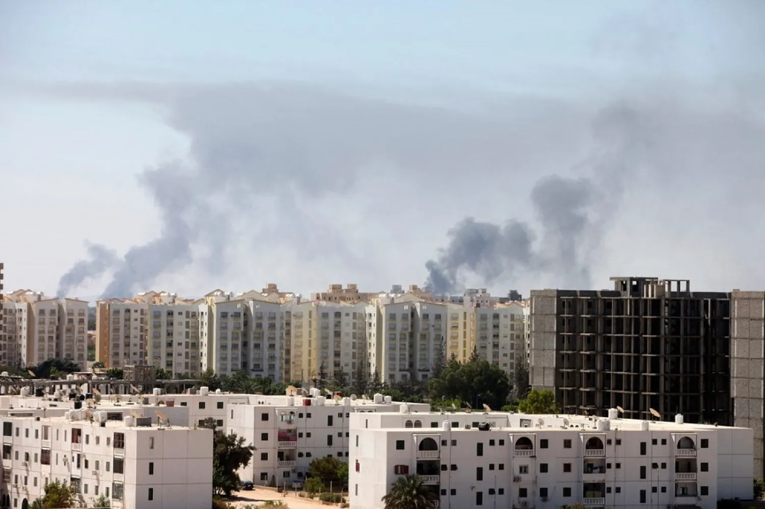Smoke rises above buildings after heavy fighting between rival militias broke out near the airport in Tripoli July 23, 2014. (Reuters)