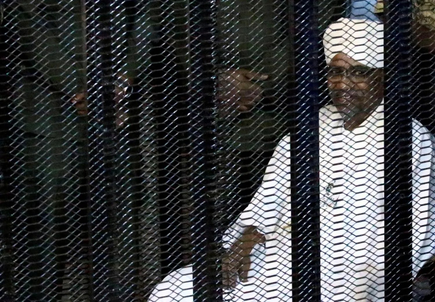 Sudan's former president Omar al-Bashir sits guarded inside a cage at the courthouse where he is facing corruption charges, in Khartoum, Sudan August 19, 2019. (Reuters)