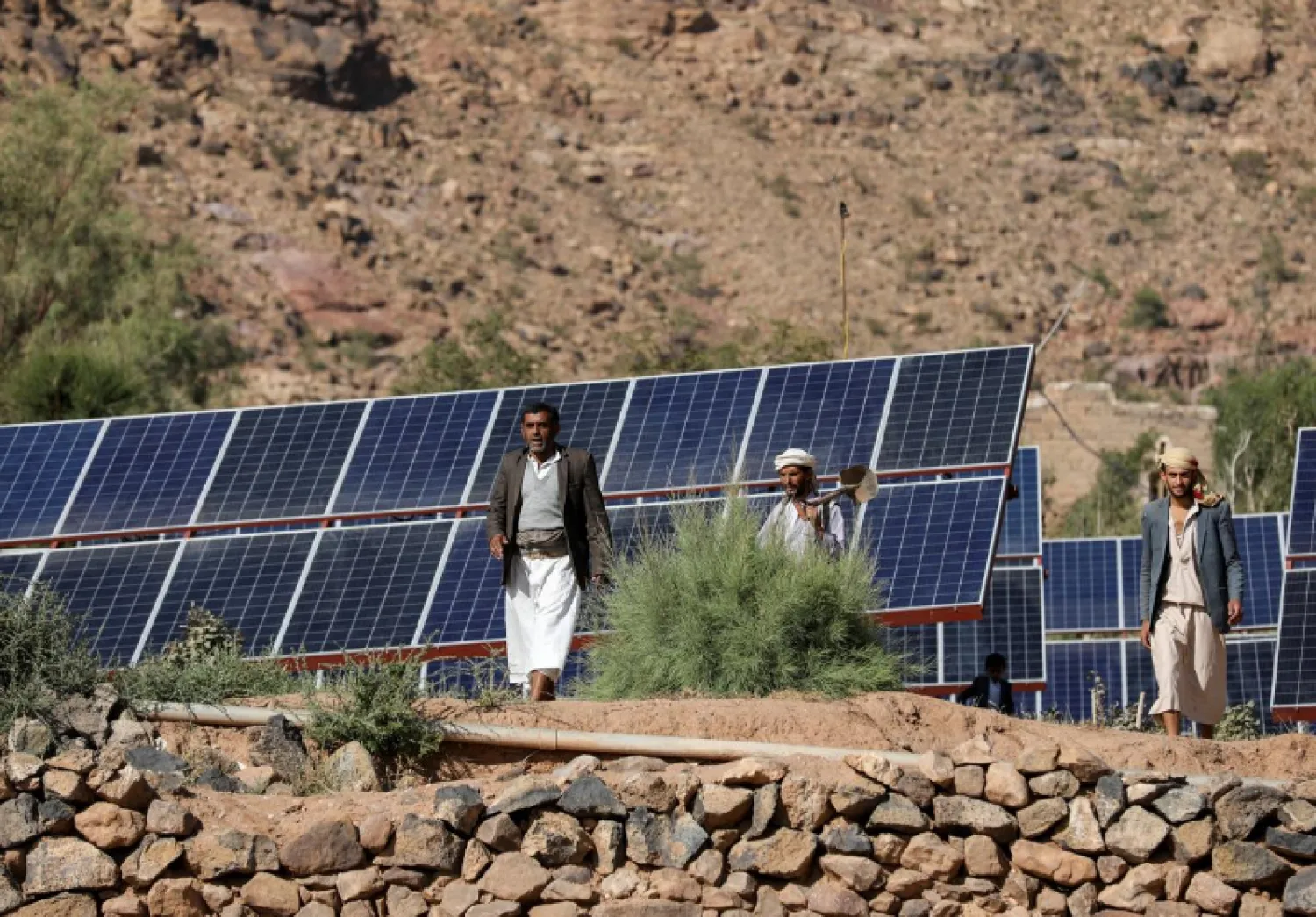 Farmers walk next to solar panels at a farmland in Wadi Dhahr near Sanaa, Yemen October 28, 2019. REUTERS/Khaled Abdullah
