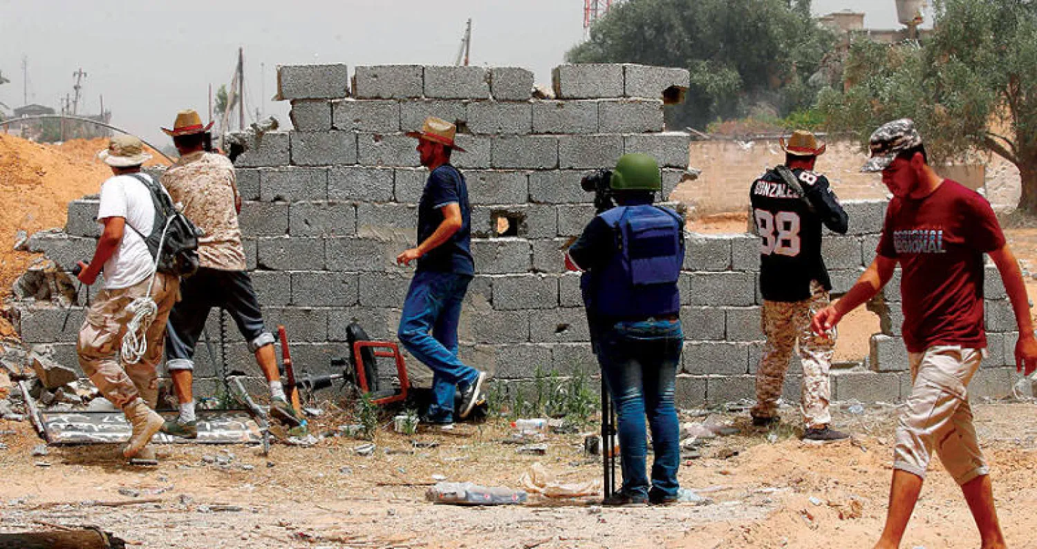 صورة أرشيفية لصحافي يغطي المعارك وسط جنود تابعين للجيش الوطني الليبي جنوب العاصمة طرابلس في يونيو الماضي (أ.ف.ب)