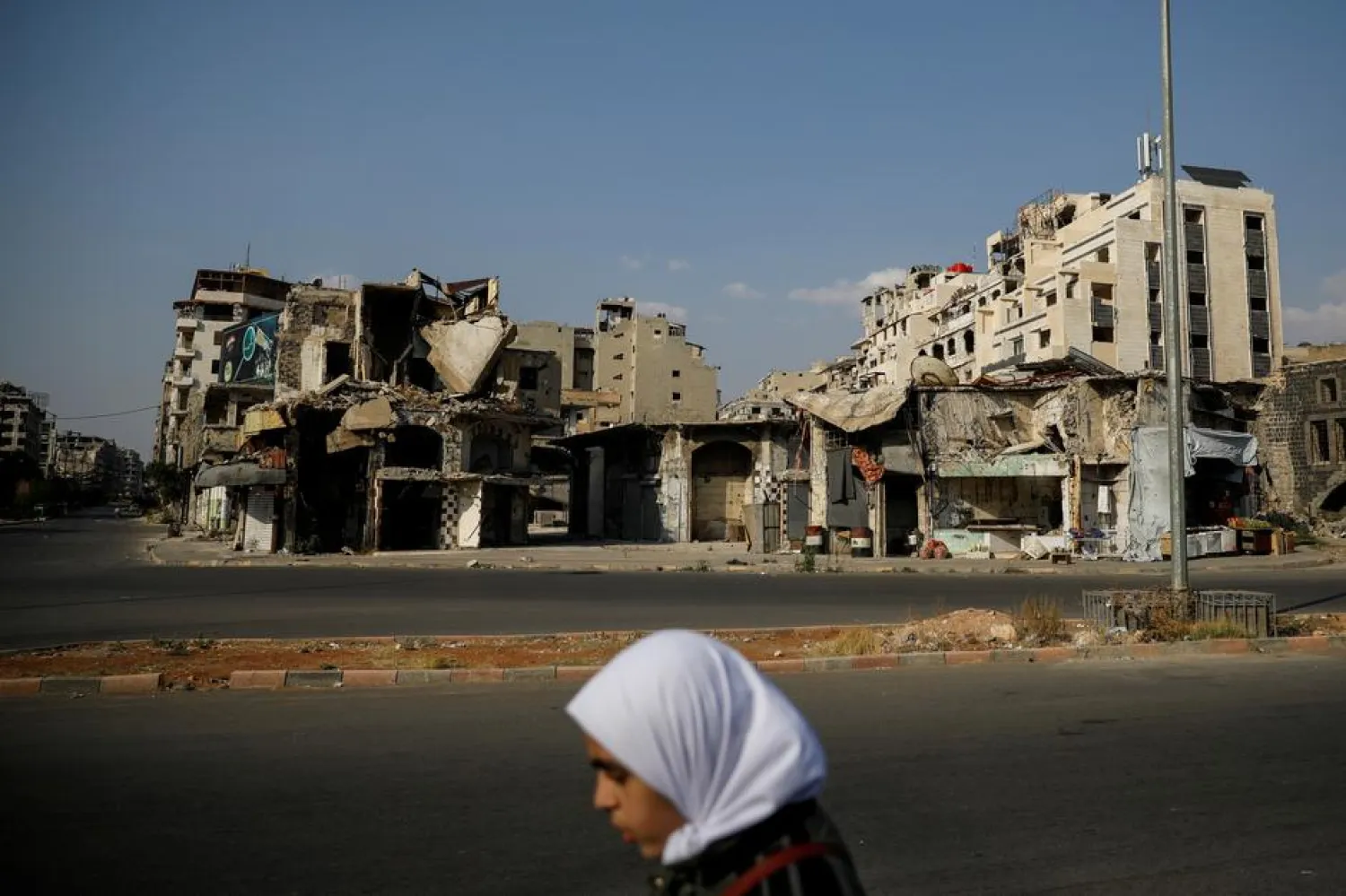 A woman walks past destroyed buildings in the regime-controlled part of Homs, Syria, September 18, 2018. REUTERS/Marko Djurica