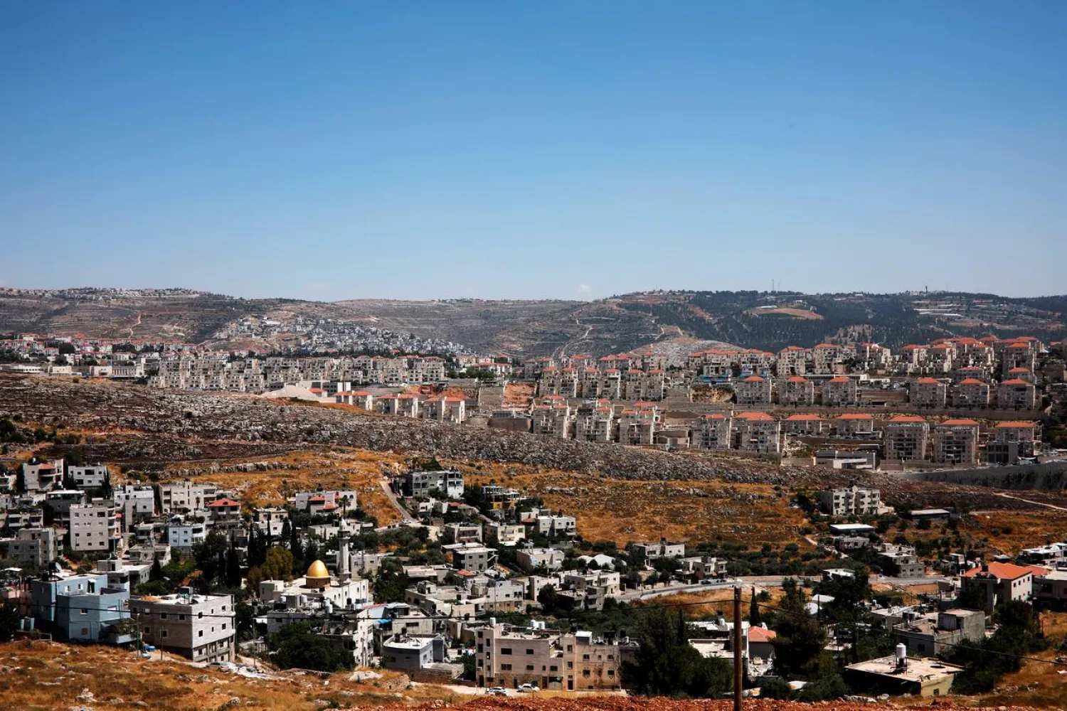 A general view shows Palestinian houses in the village of Wadi Fukin as the Israeli settlement of Beitar Illit is seen in the background, in the occupied West Bank, June, 19, 2019. Beitar Illit was built in the 1990s for Israel's Ultra-Orthodox Jewish community and is one of the largest and fastest-growing settlements in the West Bank. REUTERS/Nir Elias/File Photo