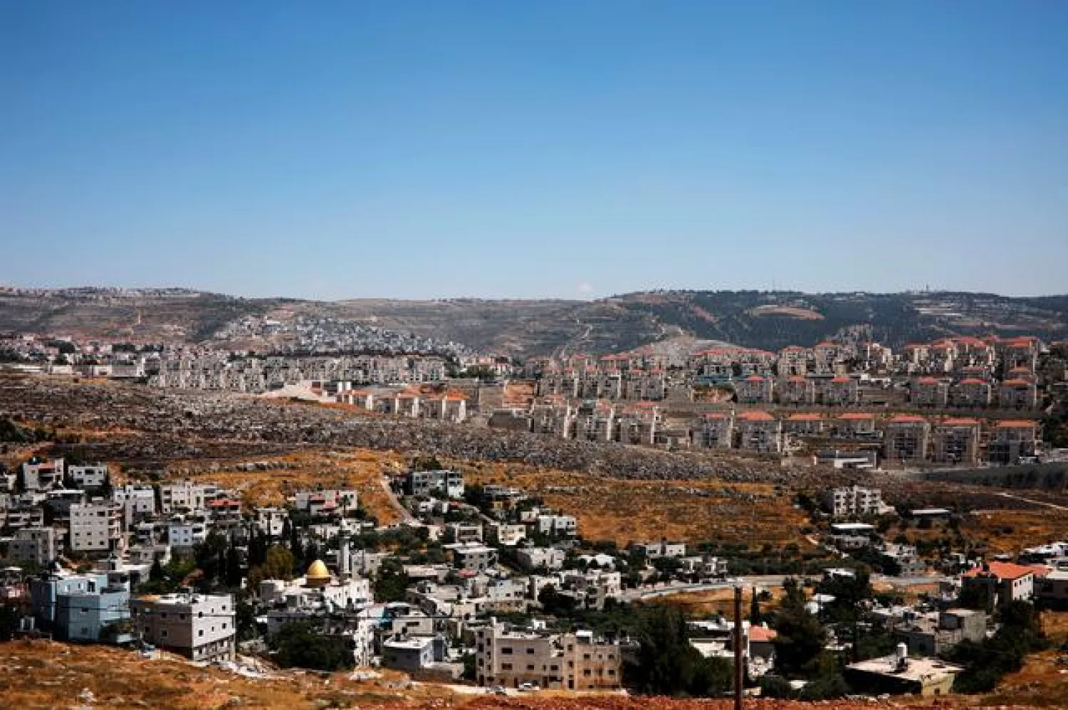 FILE PHOTO: A general view shows Palestinian houses in the village of Wadi Fukin as the Israeli settlement of Beitar Illit is seen in the background, in the occupied West Bank, June, 19, 2019. - Reuters
