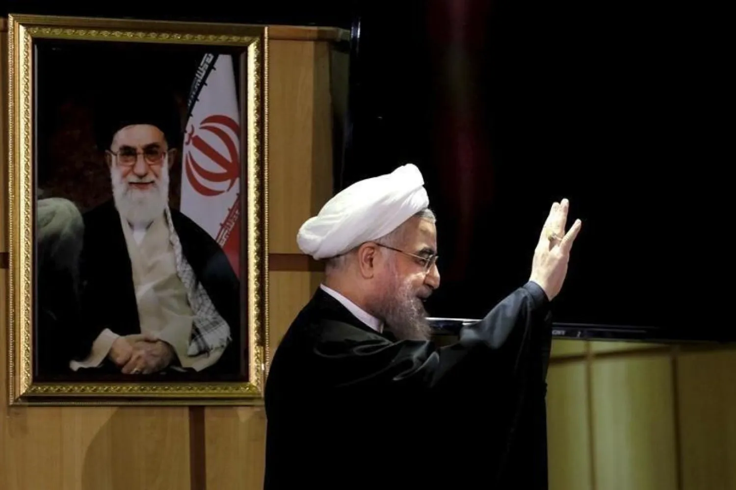 İran Cumhurbaşkanı Hasan Ruhani, İran Devrim Rehberi Ali Hamaney’in portresinin yanında poz verirken (Reuters)