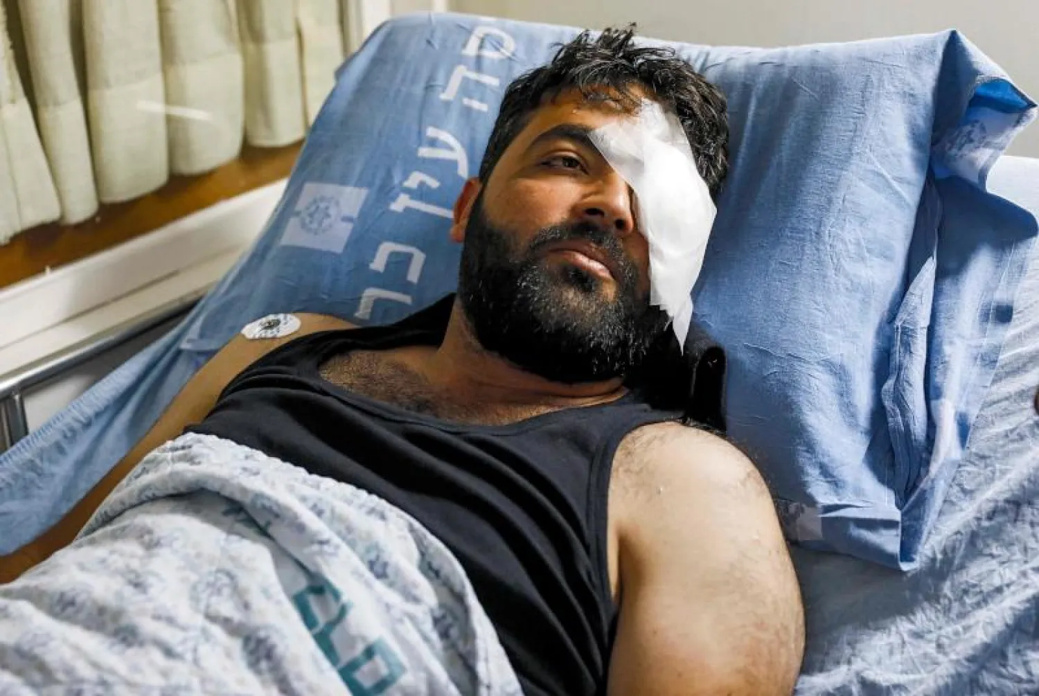 المصور الصحافي الفلسطيني معاذ عمارنة يرقد على السرير في مستشفى بالقدس (أ.ف.ب)