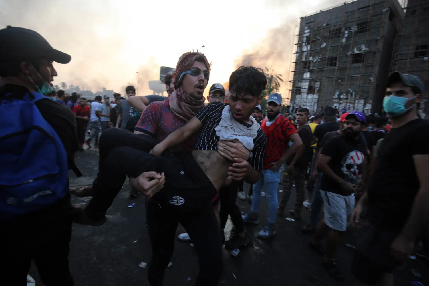An Iraqi protester carries a wounded protester during a demonstration at Tayaran square in Baghdad on October 2, 2019. AFP 