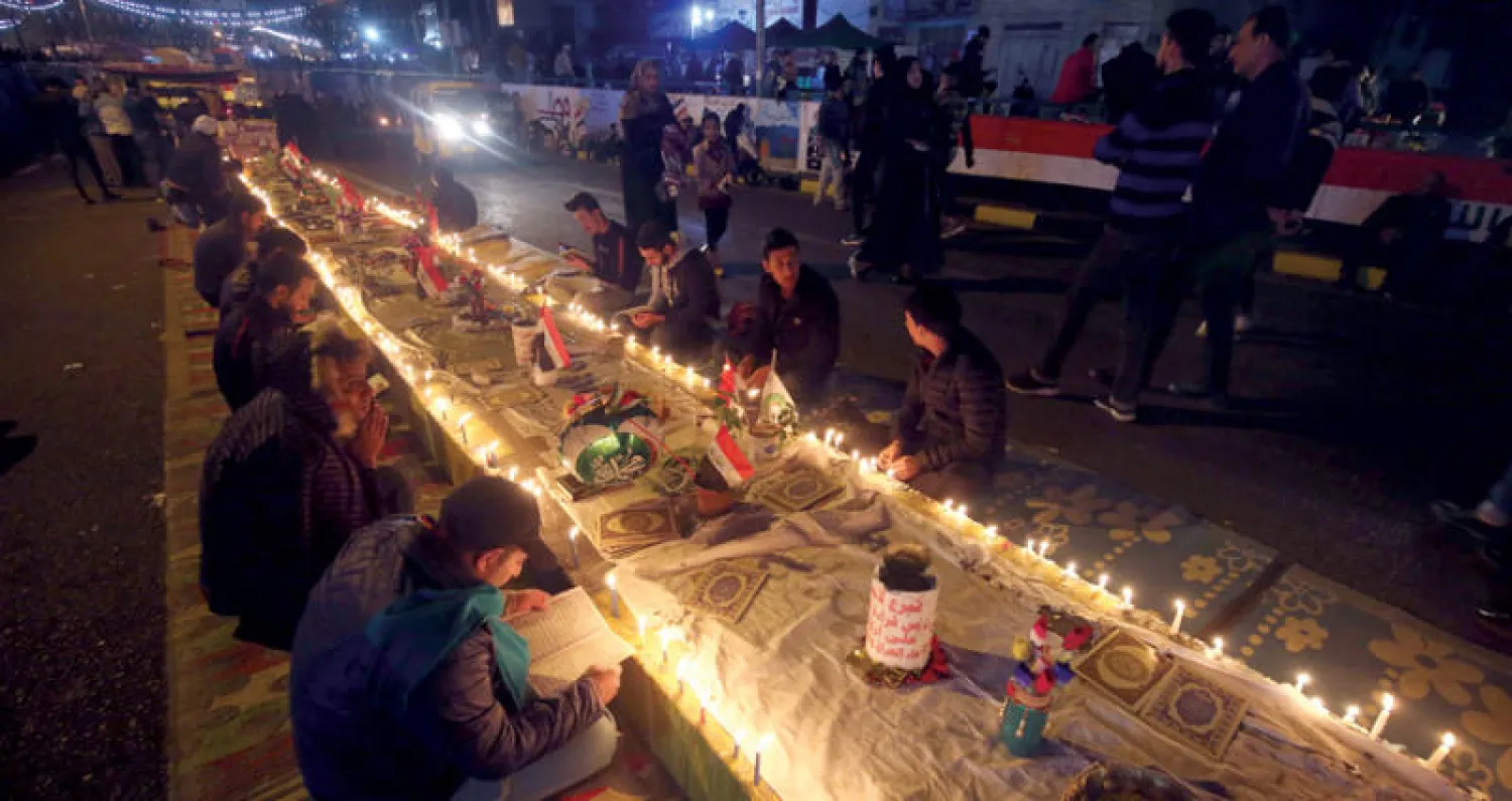 متظاهرون يوقدون الشموع خلال وقفة احتجاجية في ساحة التحرير ببغداد مساء أمس (أ.ف.ب)