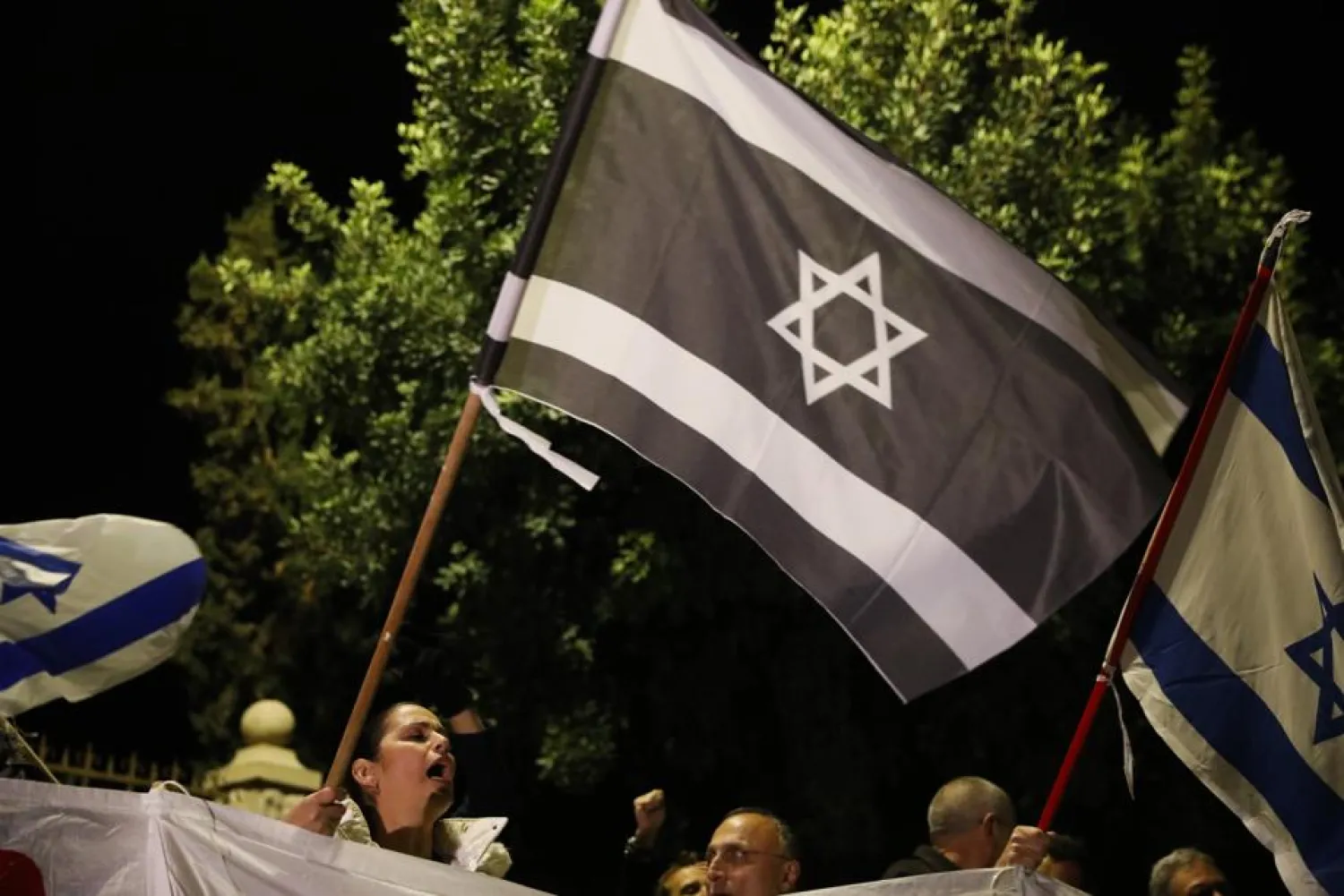 Opponents of Israeli Prime Minister Benjamin Netanyahu gather outside his residence in Jerusalem, Thursday, Nov. 21, 2019. Israel's attorney general charged Netanyahu with fraud, breach of trust and accepting bribes in three different scandals. It is the first time a sitting Israeli prime minister has been charged with a crime. (AP Photo/Ariel Schalit)