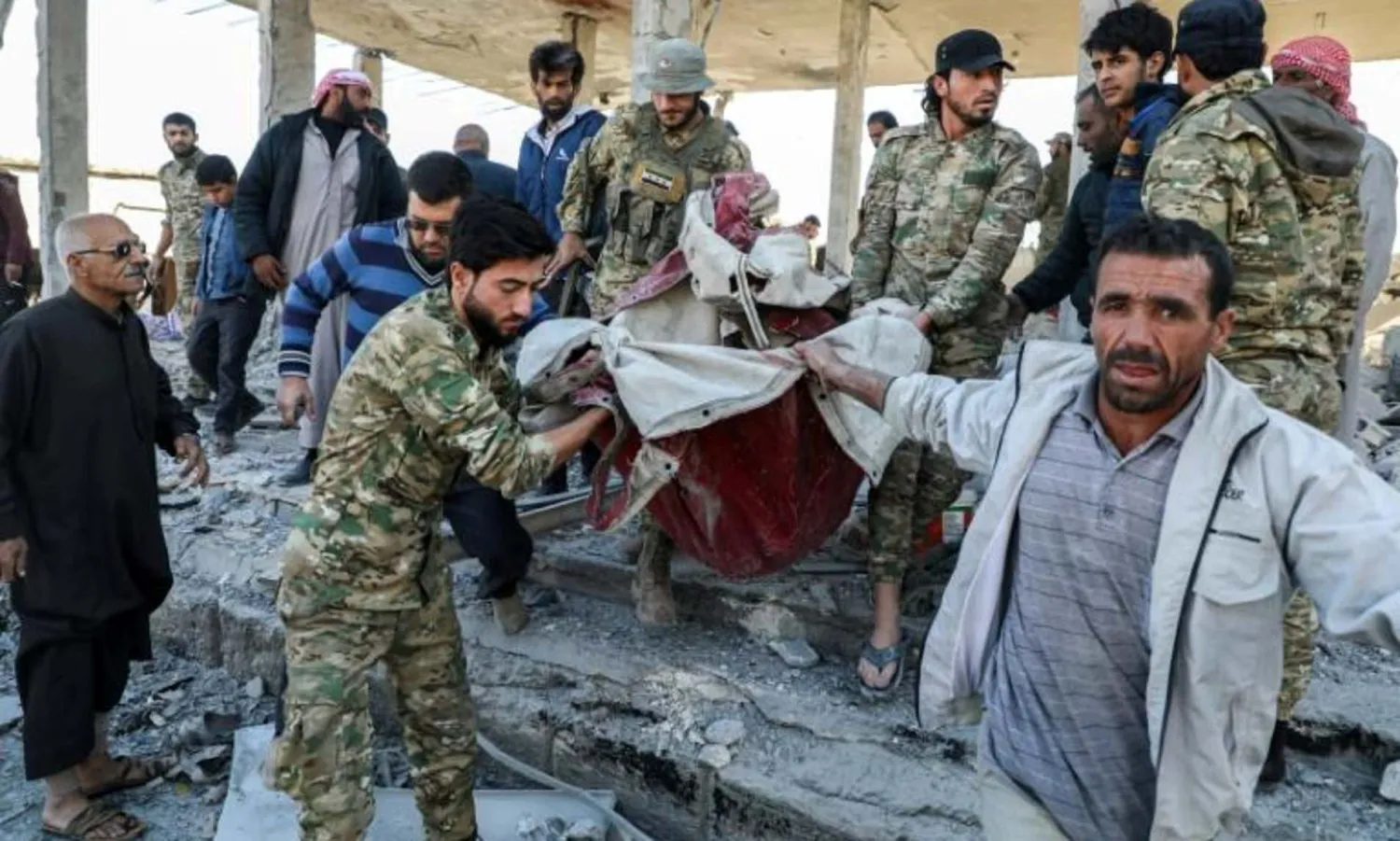 Pro-Turkish Syrian fighters carry away remains of the victims of a car bomb explosion in the northern Syrian town of Tal Abyad on Saturday | AFP