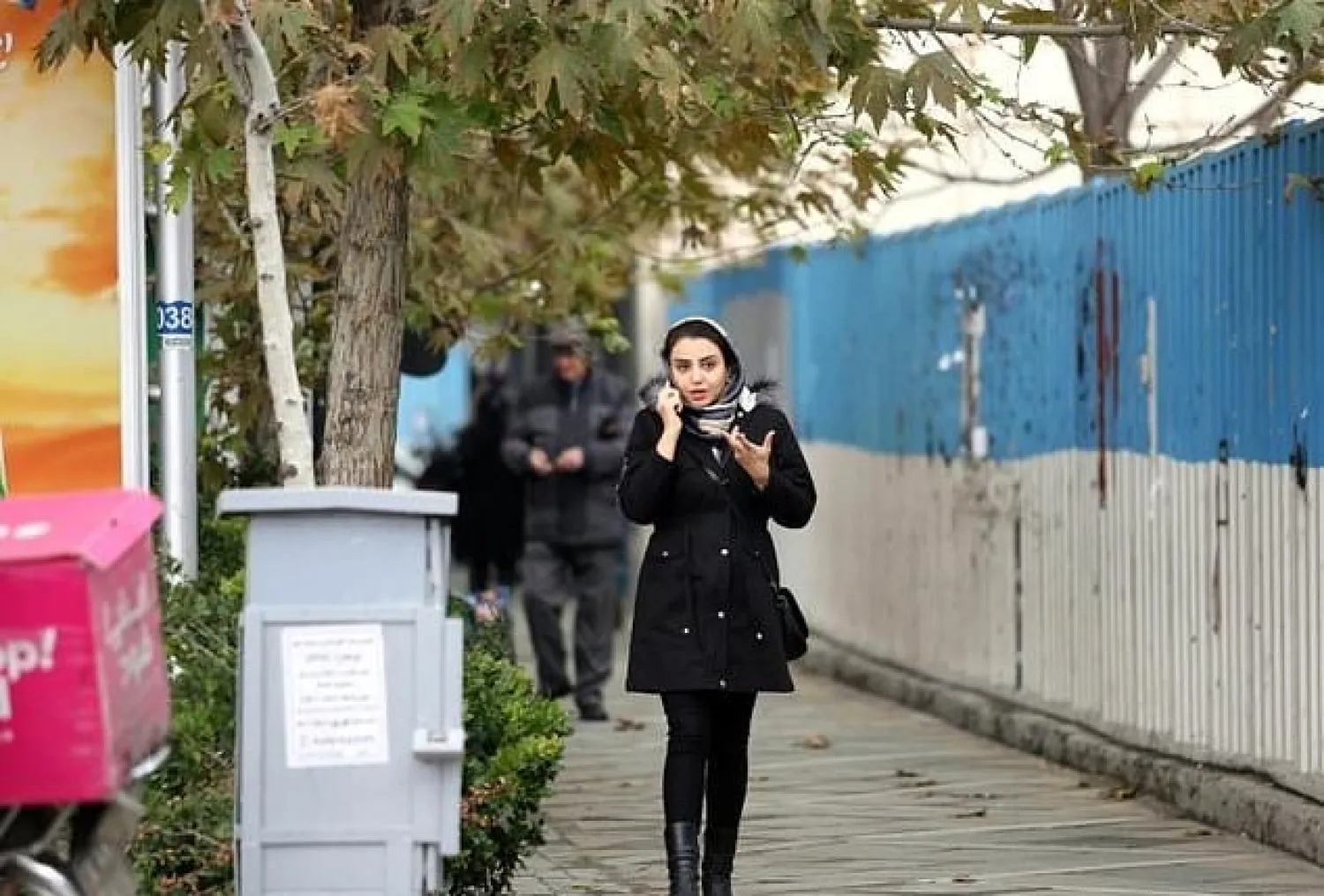 A woman makes a cell phone call while walking along a street in Tehran. AFP

