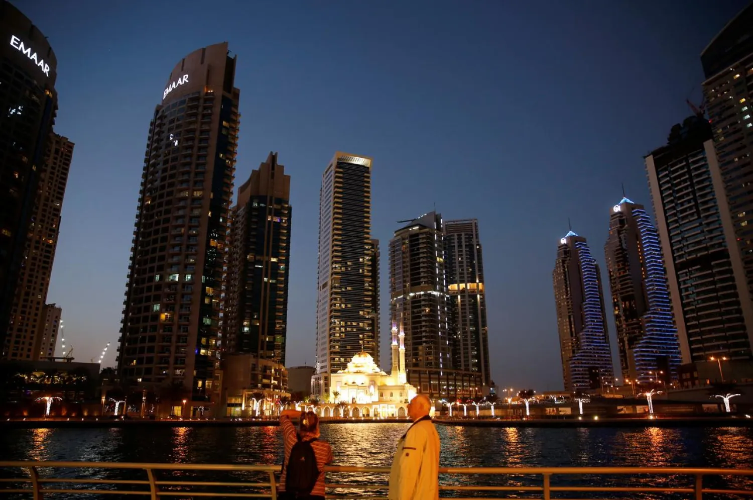 Tourist take photos of a mosque across the Dubai Marina, surrounded by high towers of hotels, banks and office buildings, in Dubai, UAE December 11, 2017. (Reuters)