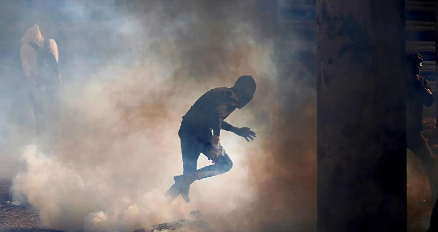 متظاهر وسط غمامة من غاز الدموع خلال مواجهة مع قوات الأمن في بغداد أمس (رويترز)