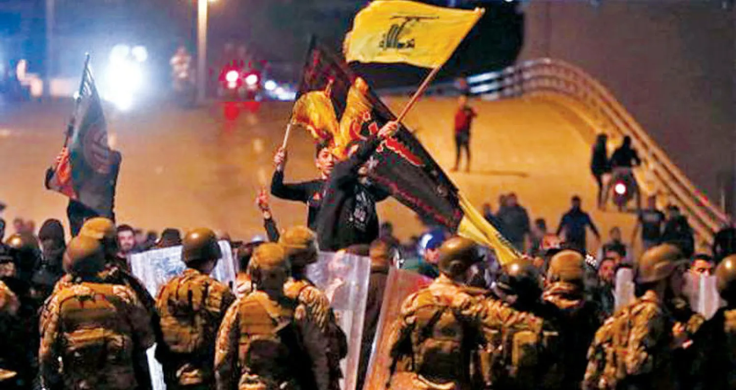 أنصار «حزب الله» وحركة «أمل» يحملون عَلميهما أمام صف من الجنود خلال الهجمات على المحتجين وسط بيروت الليلة قبل الماضية (أ.ف.ب)