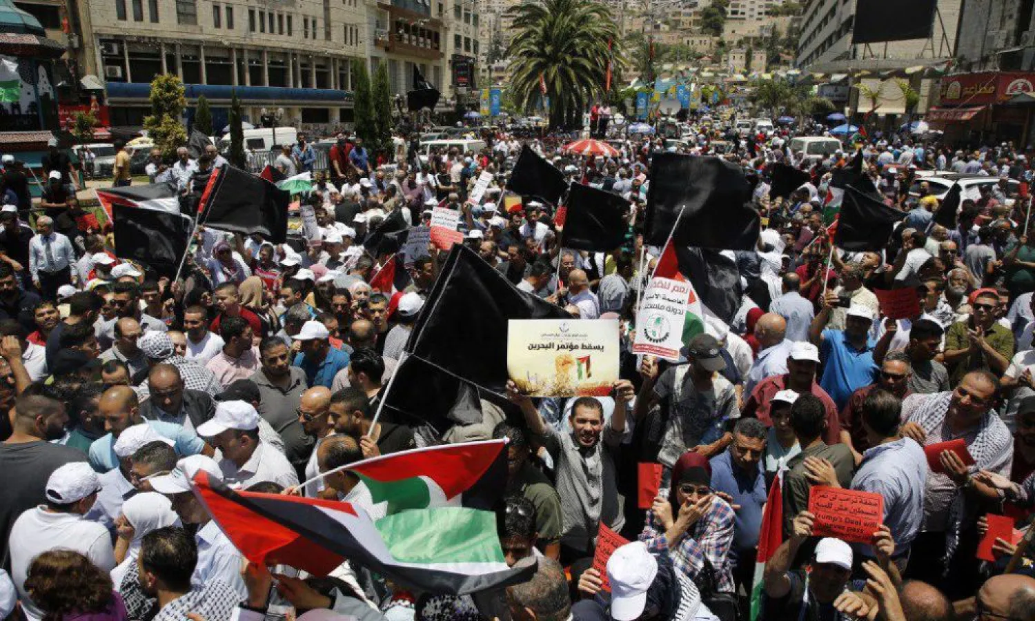 Palestinian demonstrators carry banners and national flags during a protest against the US-sponsored Middle East economic conference that opened in Bahrain, in the Israeli-occupied West Bank city of Nablus on June 25, 2019. (Jaafar Ashtiyeh/AFP)
