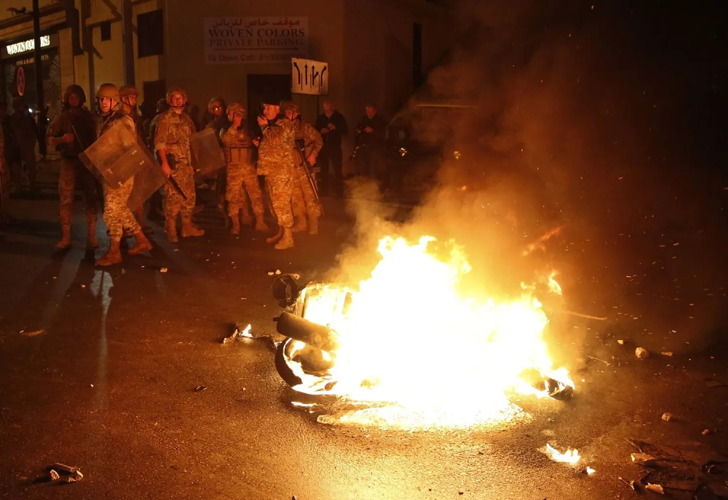 Lebanese soldiers stand near a motorcycle that was set on fire by protesters, during a clash between Hezbollah and Amal supporters and anti-government protesters, in Beirut, Nov. 25, 2019. (AP)