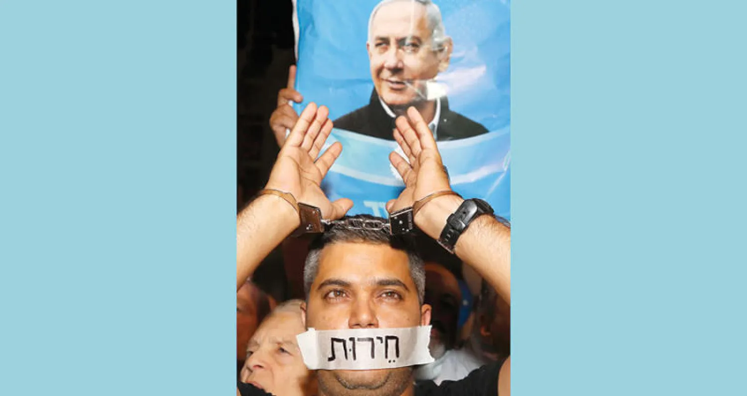 متظاهر مؤيد لنتنياهو في تل أبيب تحت لافتة شعارها «لا للانقلاب» (أ.ف.ب)