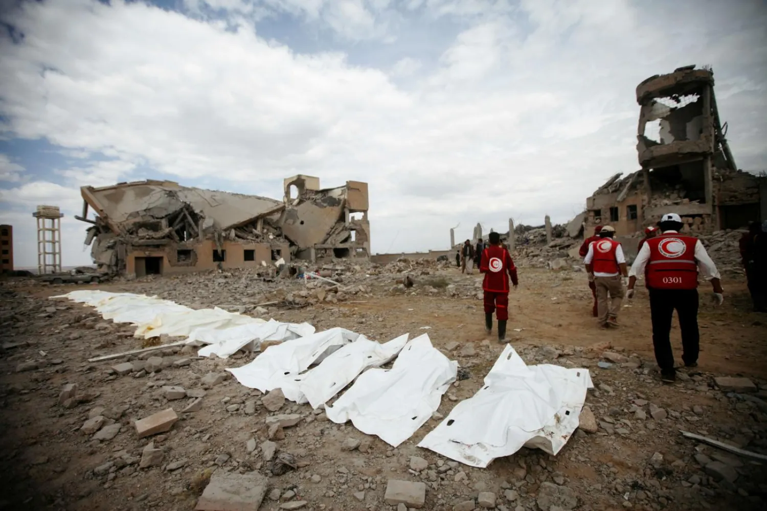 Red Crescent medics walk next to bags containing the bodies of victims of Saudi-led air strikes on a Houthi detention centre in Dhamar, Yemen (Reuters)
