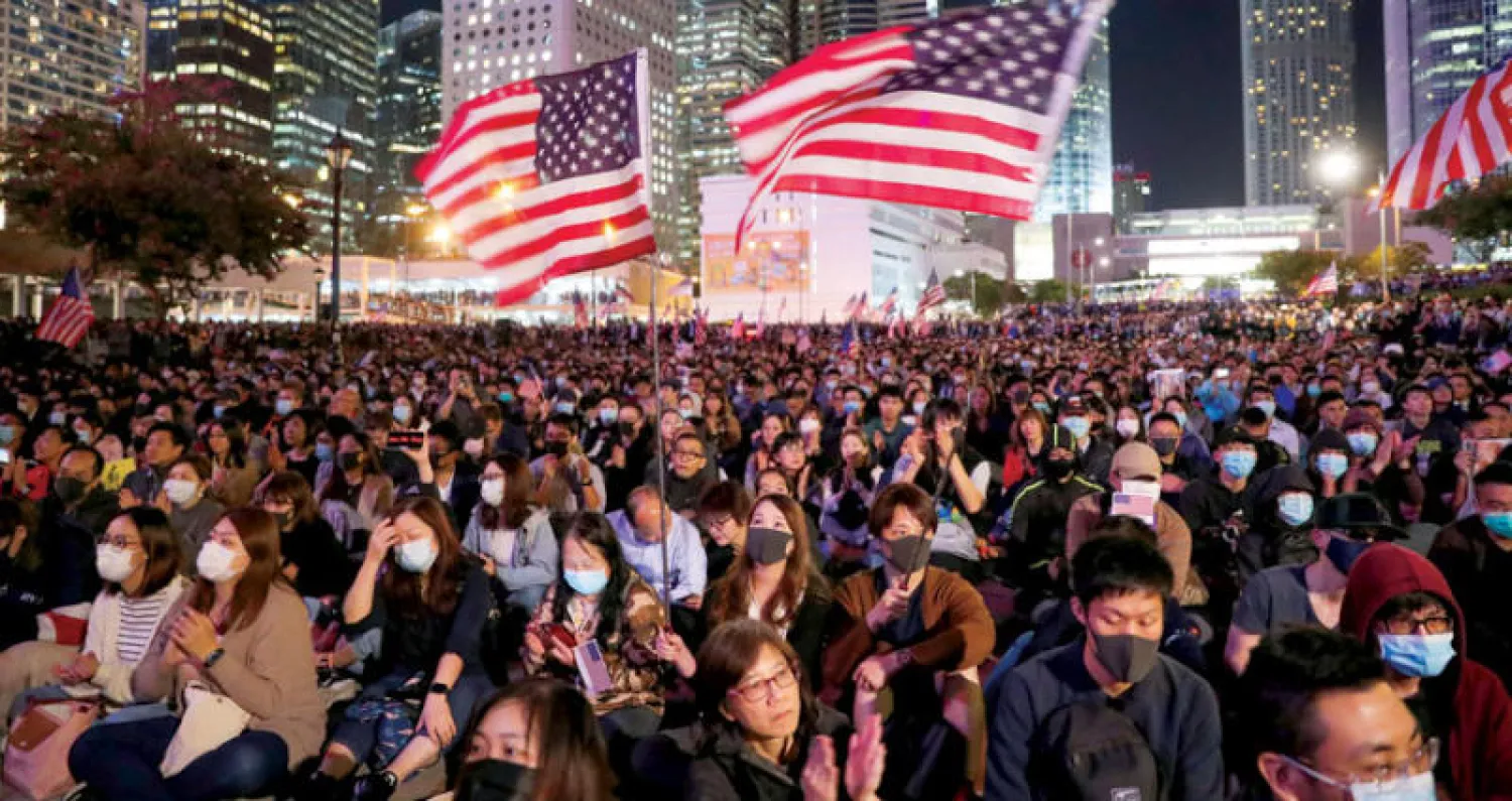 متظاهرون يحملون أعلاماً أميركية ترحيباً بموقف واشنطن تجاه هونغ كونغ أمس (رويترز)