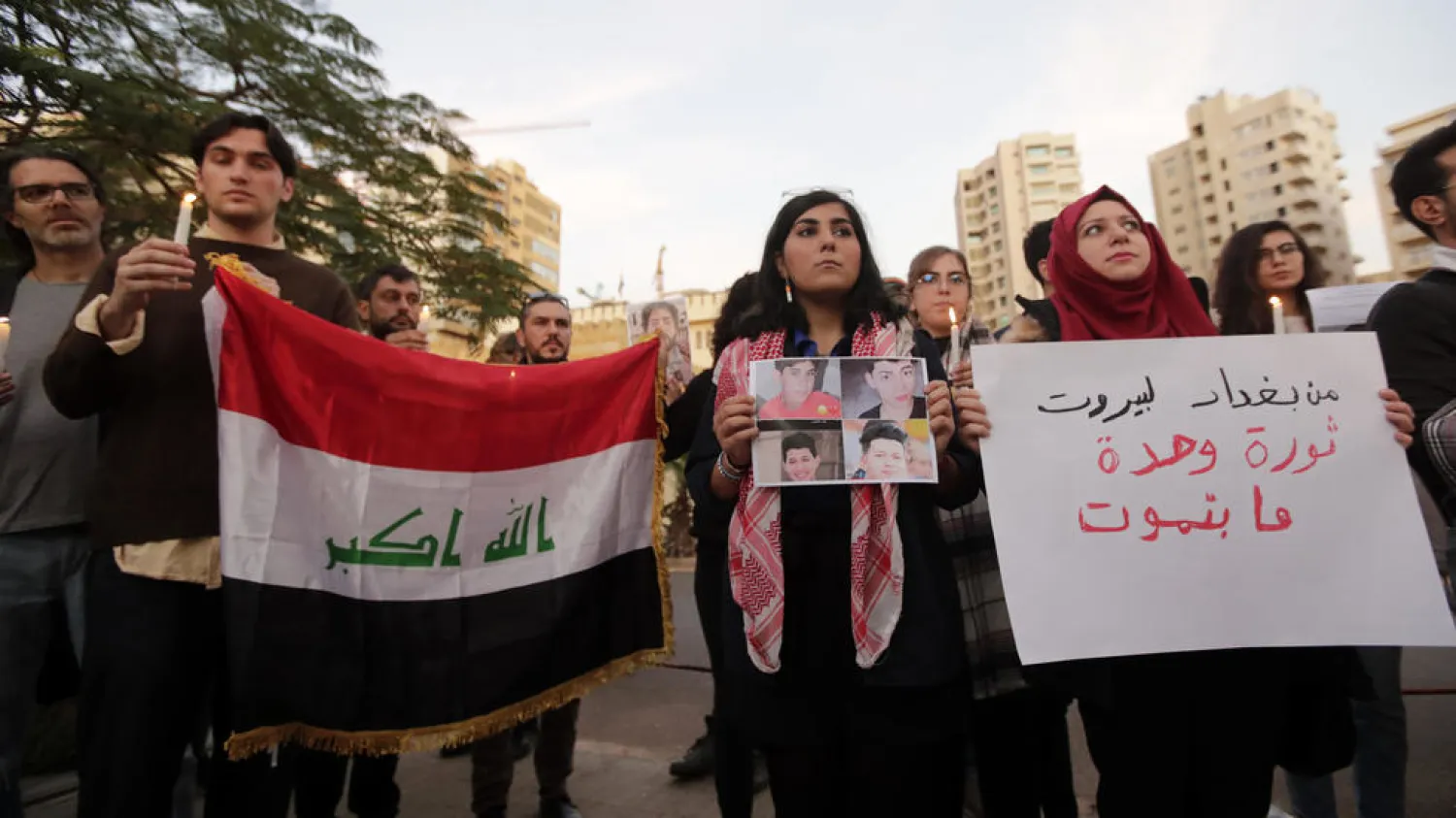 Lebanese protesters at the vigil carry the Iraqi national flag and a poster reading ‘From Baghdad to Beirut, one revolution that will not die. (AFP)