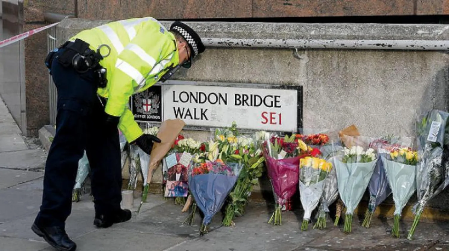 Londra'da terör saldırısının düzenlendiği yere çiçek koyan bir polis memuru (Reuters)