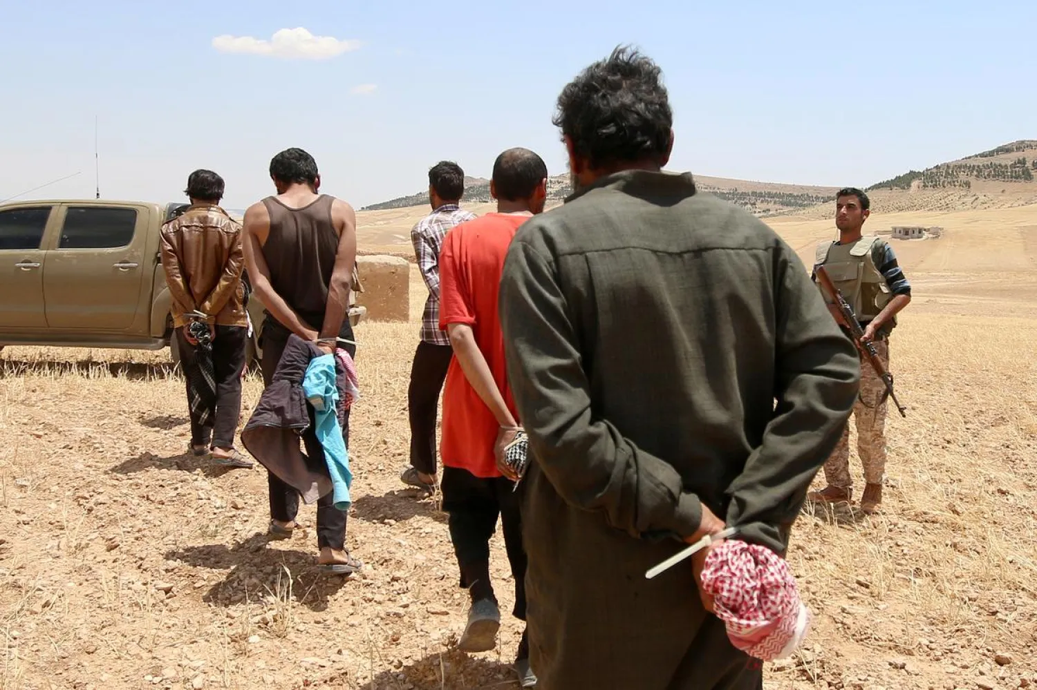 Men, who the Democratic Forces of Syria fighters claim are ISIS fighters, walk as they are taken prisoners. (Reuters)