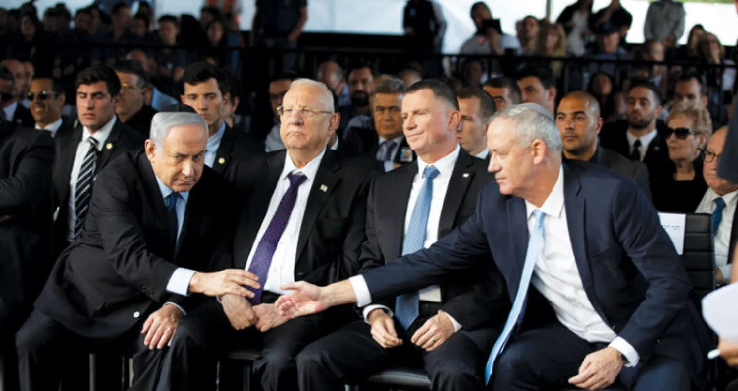 الرئيس الإسرائيلي ريفلين (الثاني إلى اليسار) في احتفال ذكرى مقتل رابين الشهر الماضي بينما يتصافح غانتس ونتنياهو (رويترز)