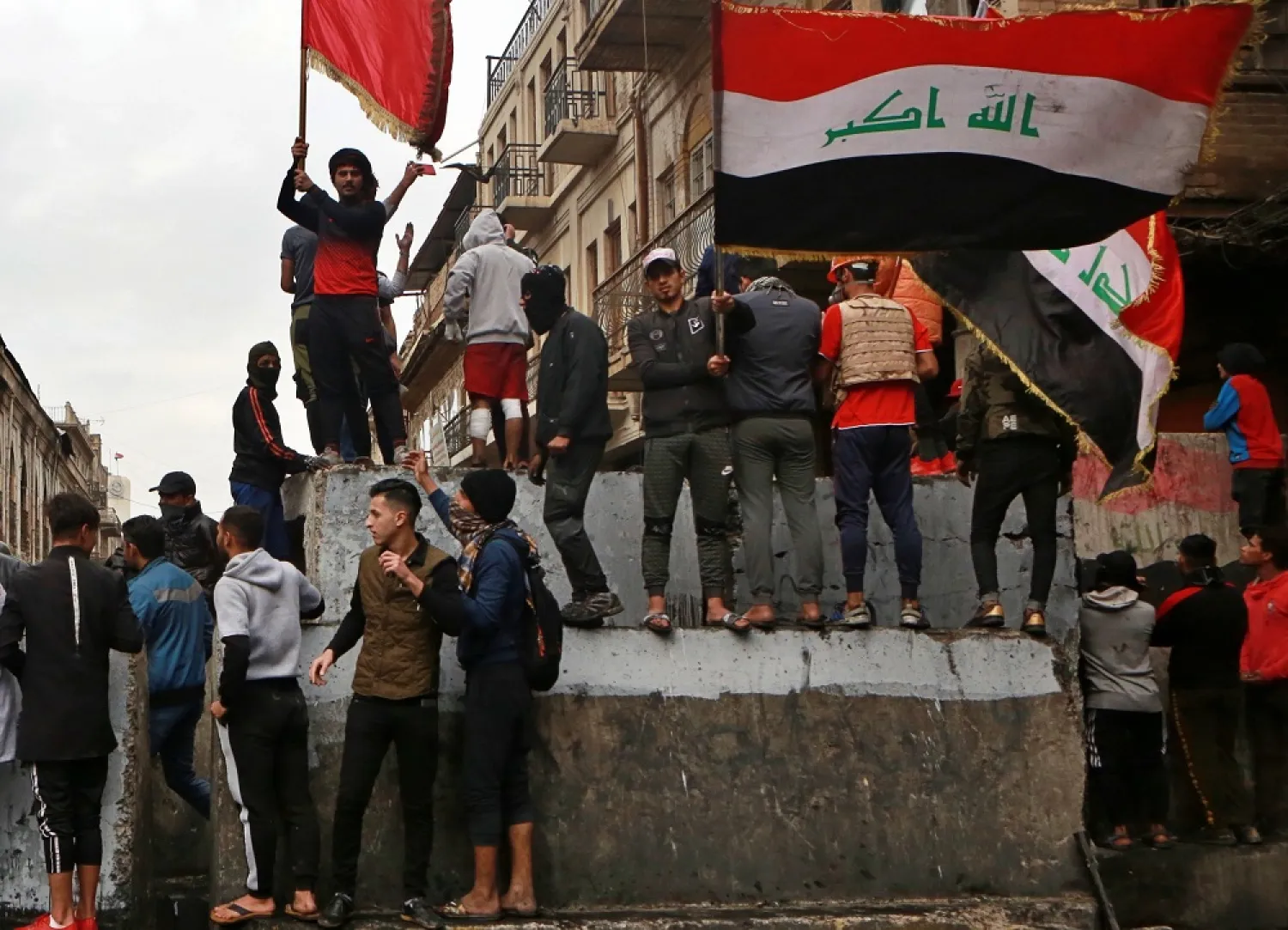 Anti-government protesters gather on barriers set up by security forces to close Rasheed Street during ongoing protests in Baghdad, Iraq, Tuesday, Dec. 3, 2019. (AP)