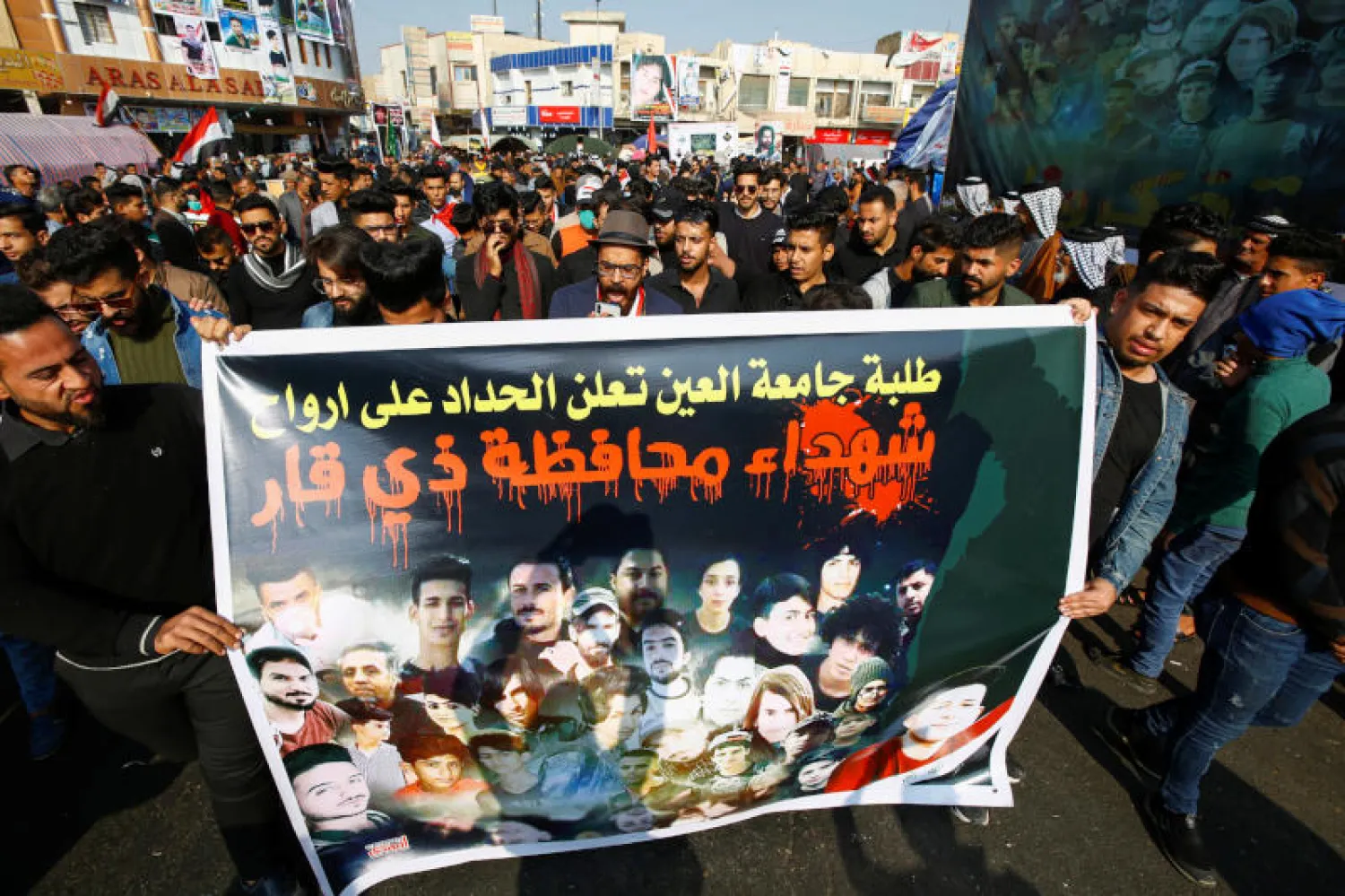 متظاهرون في مدينة الناصرية بجنوب العراق يحملون صورة لأشخاص سقطوا قتلى خلال الاحتجاجات (رويترز)