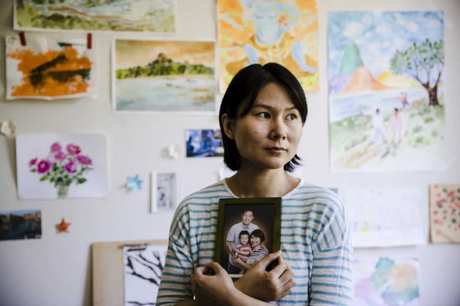 In this Wednesday, May 9, 2018 file photo, Hua Qu, the wife of detained Chinese-American Xiyue Wang, poses for a photograph with a portrait of her family in Princeton, N.J. (AP Photo/Matt Rourke, File)