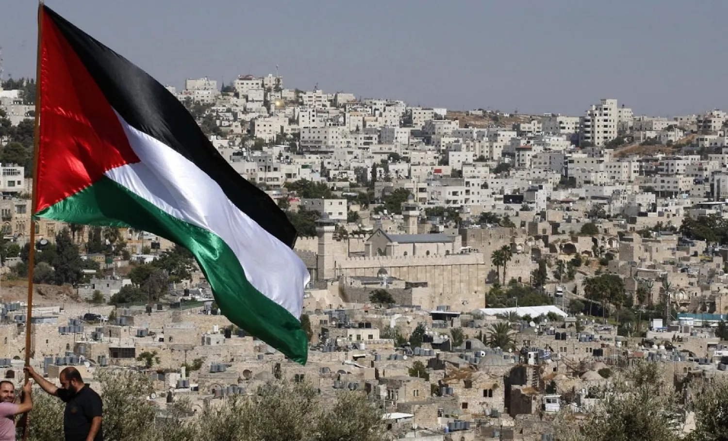 Activists in Hebron set up Palestinian flag overlooking the Israeli settlement of Tel Rumeida in occupied West Bank. (AFP)