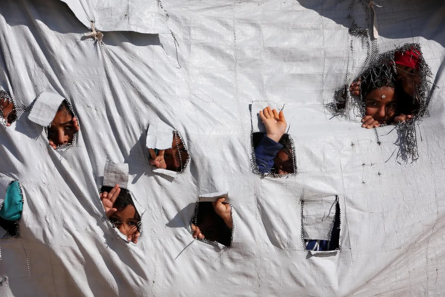 Children look through holes in a tent at al-Hol displacement camp in Hasaka governorate, Syria April 2, 2019. Picture taken April 2, 2019. REUTERS/Ali Hashisho