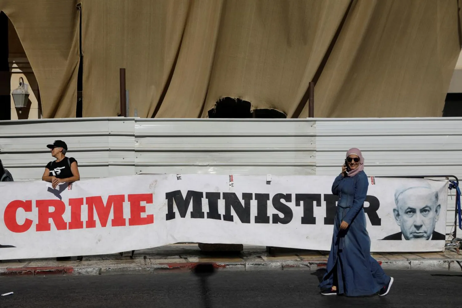 A woman walks past a banner depicting Israeli PM Benjamin Netanyahu and the words 'Crime Minister' outside the Justice Ministry, in Jerusalem October 3, 2019. (Reuters)