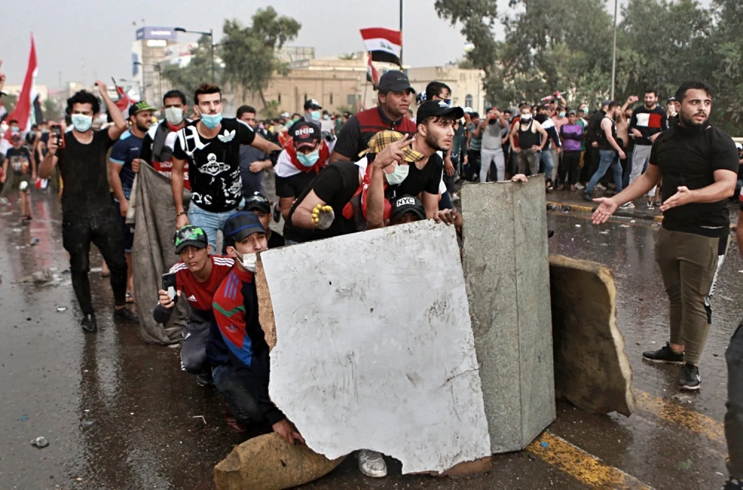 Anti-government protesters take cover as security forces open fire during a demonstration in Baghdad on October 25, 2019. (AP)
