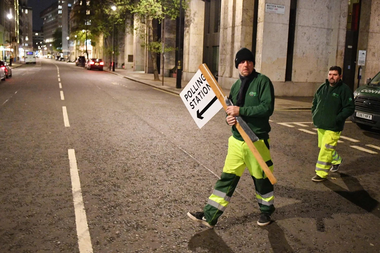 عاملان يضعان لافتة ارشادية للمصوتين (أ.ف.ب)