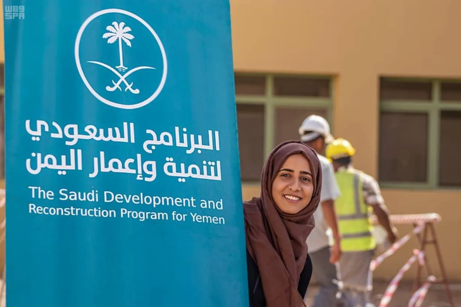A Yemeni woman poses by a poster of the Saudi Development and Reconstruction Program for Yemen. (SPA)