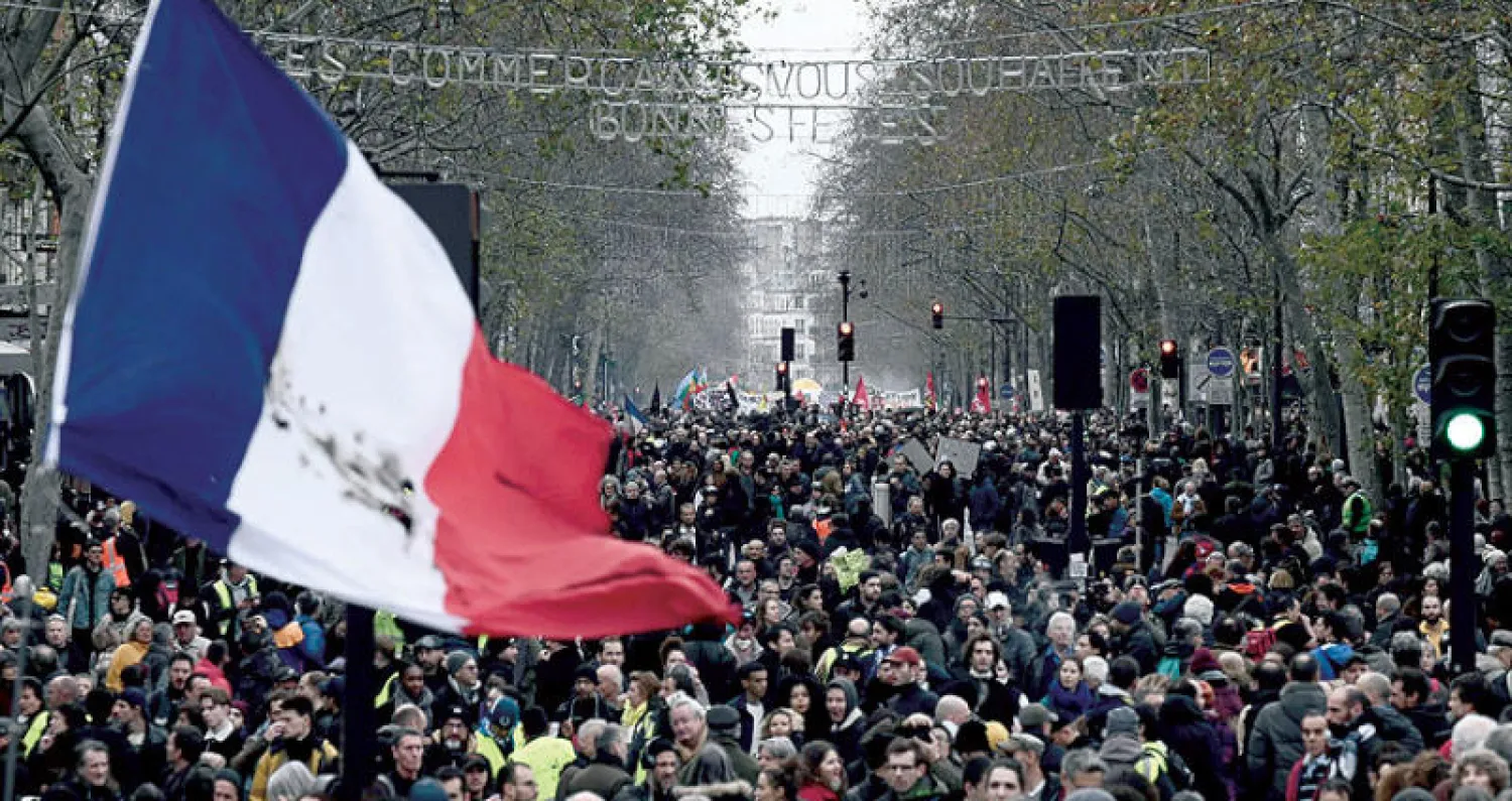 متظاهرون يحملون علماً فرنسياً ضخماً في باريس أمس (أ.ف.ب)