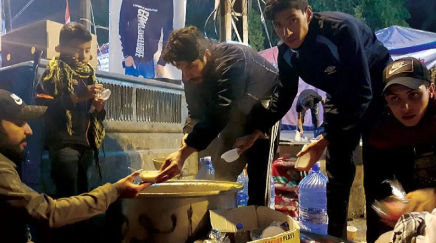 A man distributes lentil soup at Baghdad's Tahrir Square. Asharq Al-Awsat